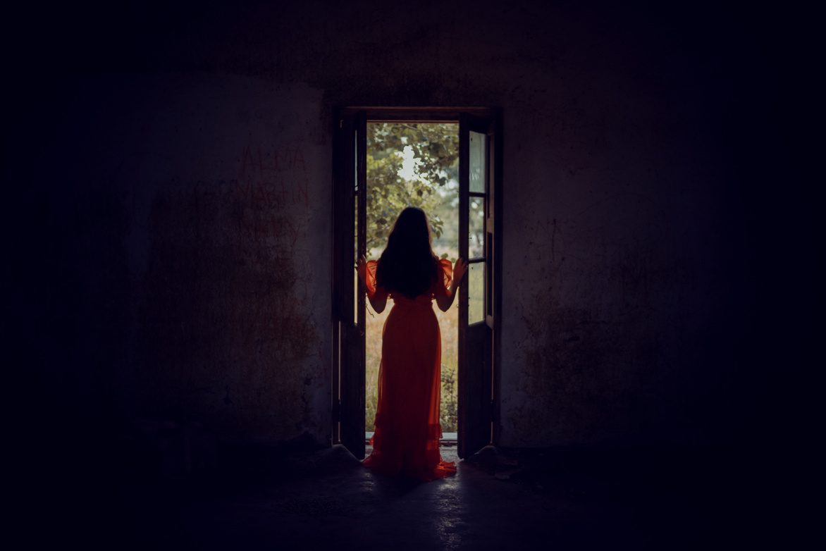 A woman in a red dress standing in an open doorway